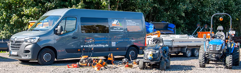 Dunkelblauer Lieferwagen mit Schilling-Logo, Gartengeräte und zwei Traktoren stehen auf graveligem Boden vor Büschen.